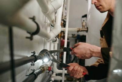 Technician inspecting commercial plumbing pipes in Redwood City