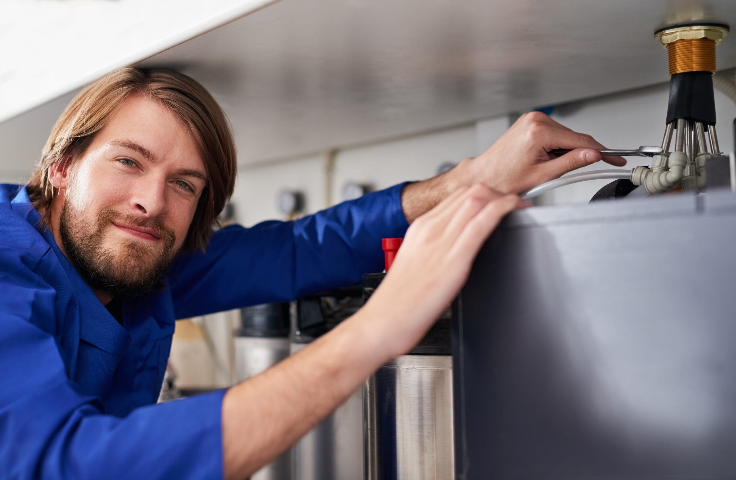 Technician servicing a residential water heater tank in Redwood City